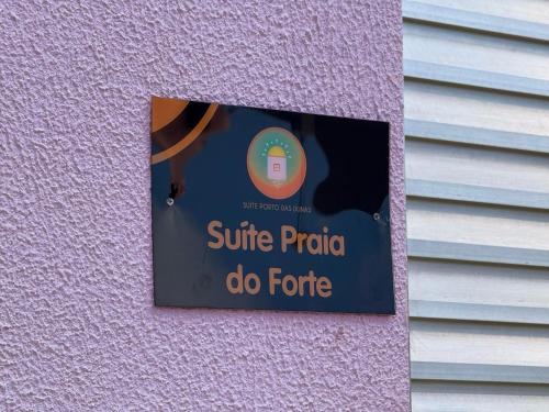 a sign on the side of a pink wall at Suíte Porto das Dunas in Salvador