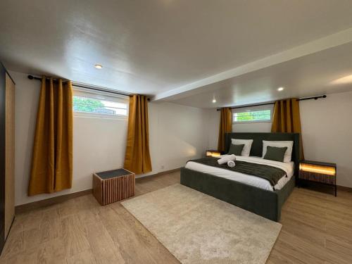 a bedroom with a large bed and two windows at Au Grand Cèdre - garden and billiard with family in Tacoignières