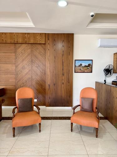 two orange chairs in a waiting room with wood panels at Amchit Grand Hotel in Al Qarfī