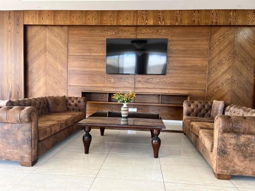 a living room with two couches and a tv at Amchit Grand Hotel in Al Qarfī