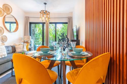 a dining room with a glass table and yellow chairs at Thematic beach apartment in CapCana area in Punta Cana