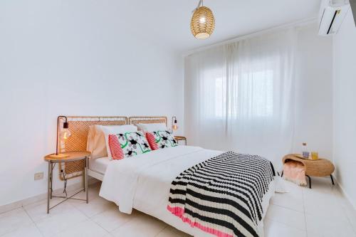 a white bedroom with a large bed with colorful pillows at Brisa Algarvia 2 in Faro