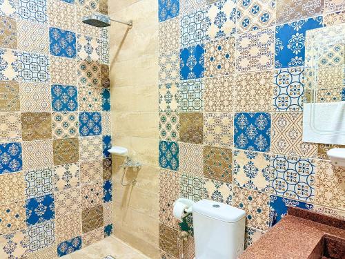 a bathroom with a toilet and a tiled wall at Bab Al Shams Palace in Luxor
