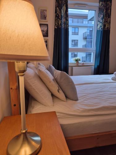 a bedroom with a bed with a lamp and a window at Maczka Apartament in Łódź