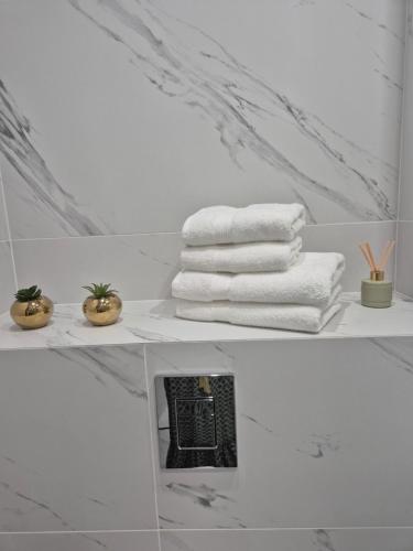 a white bathroom with towels on a shelf at Maczka Apartament in Łódź