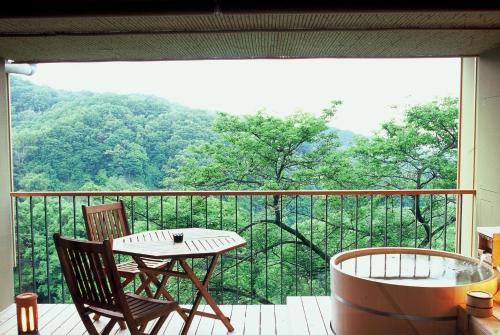 a balcony with a table and chairs and a large window at Kakimotoya in Sango