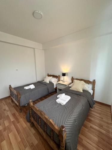 two twin beds in a room with wooden floors at Departamento temporal zona Bv Galvez con chochera in Santa Fe