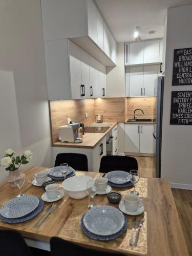 a kitchen with a wooden table with plates on it at Maczka Apartament in Łódź