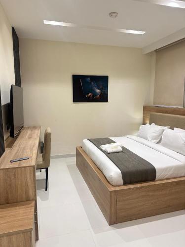 a bedroom with a bed and a desk and a television at Adar Hotel in Lagos