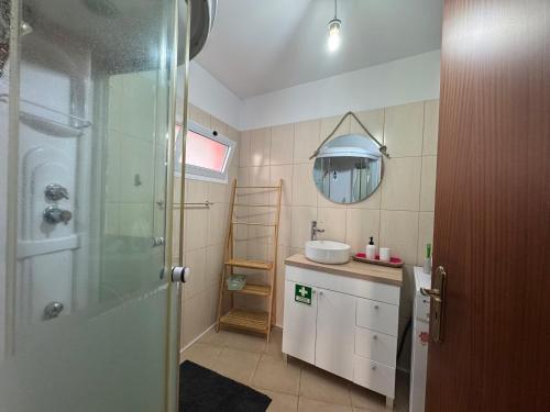 un bagno con doccia, lavandino e specchio di Pôr do Sol a Estreito da Calheta