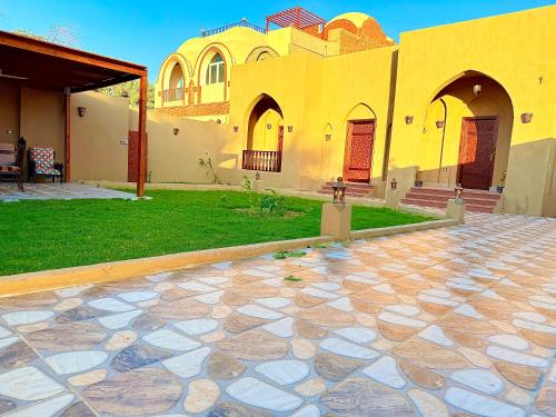 a house with a yard with a stone patio at Bab Al Shams Palace in Luxor