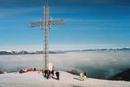 ein Kreuz auf dem Gipfel eines Berges mit Wolken in der Unterkunft Bella 2 Lupeni in Lupeni