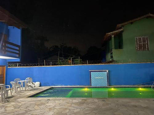 a swimming pool at night with a blue wall at Chalés do Mako in São Sebastião