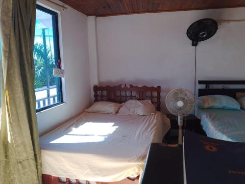 a bedroom with a bed and a window with a fan at Hotel Volga in Puerto López