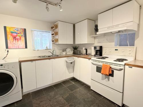 a kitchen with white cabinets and a washer and dryer at walk distance to kits beach 2bedrooms only for you in Vancouver
