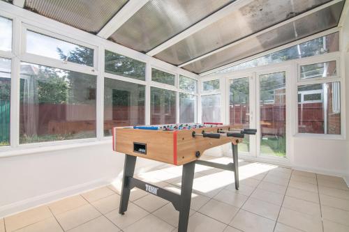 a ping pong table in a room with windows at 5 BD - Large House Oadby in Oadby