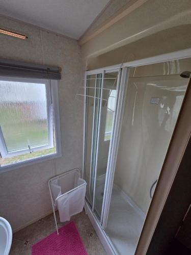 a bathroom with a shower and a sink and a window at St Osyth, Clacton-on-sea, Cozy Beach side Caravan, Wifi, Tea and Coffee, Parking included in Saint Osyth
