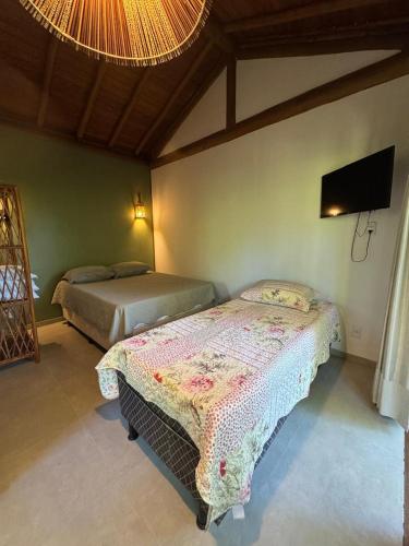 a bedroom with two beds and a flat screen tv at Suíte 3 Privativa Taipu de Fora in Barra Grande