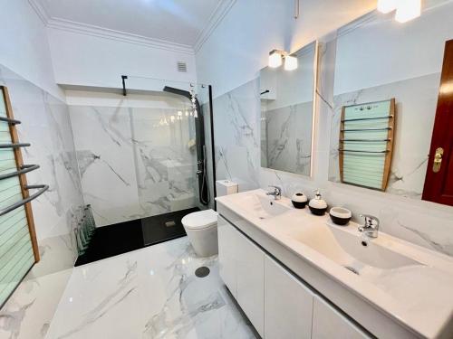 a white bathroom with a sink and a toilet at Apartamento da Torre in Mondim de Basto