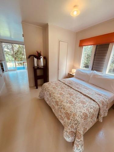 ein Schlafzimmer mit einem Bett in einem Zimmer mit Fenstern in der Unterkunft Mango Grove Cottage in Rarotonga