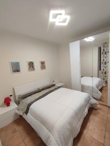 a white bedroom with a bed and a mirror at Appartamento vicino alla madonnina di tortona in Tortona