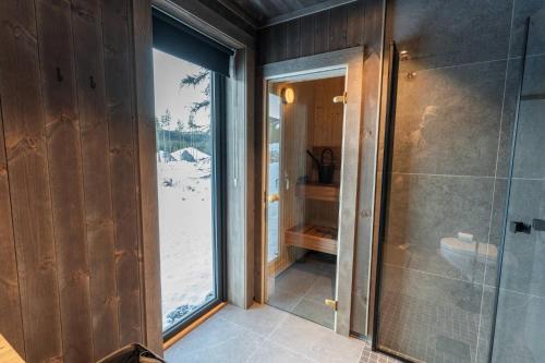 a bathroom with a shower and a large window at Luxury holiday home, skiing, sauna, remote office in Nystølen