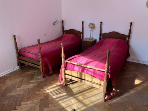 two beds in a bedroom with pink sheets at Villa Selva Mid-century Design House Vicente López in Vicente López