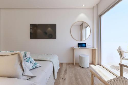 a white living room with a couch and a mirror at Hotel Moré in Alcudia