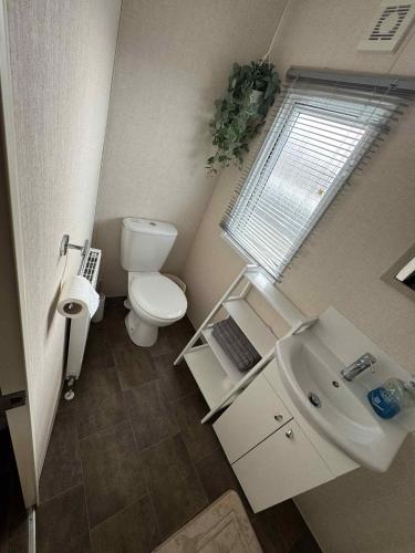 a small bathroom with a toilet and a sink at Pebble Breeze in Ingoldmells