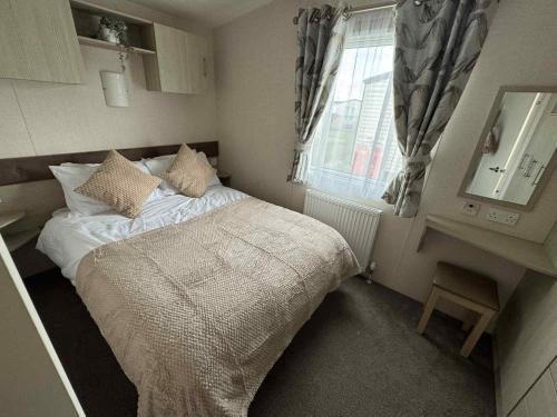 a small bedroom with a bed and a window at Pebble Breeze in Ingoldmells