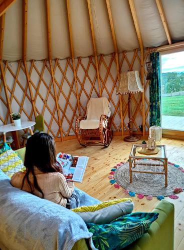 a young girl sitting on a couch in a yurt at Glamping Niebiańska Osada Jurty Dolnośląskie & SPA in Polanica-Zdrój