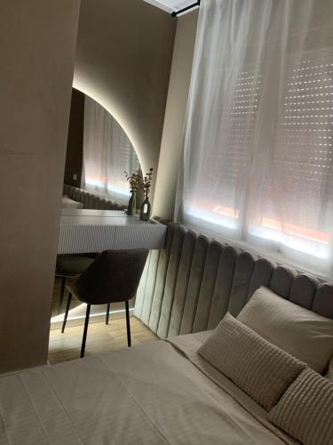 1 dormitorio con cama, mesa y ventana en Résidence du centre 8, en Kragujevac