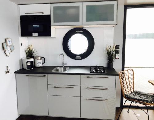 a small kitchen with a sink and a mirror at Hausboot Hafenprinz Lübeck in Brodten