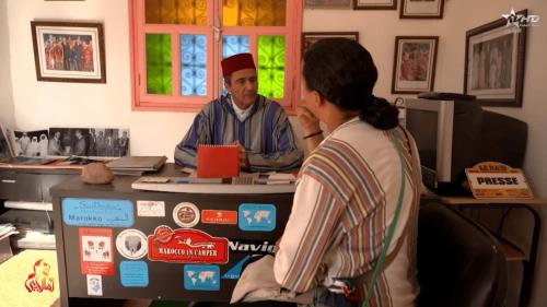 a man and a woman sitting at a desk with a computer at Camping Granit Rose in Tafraoute