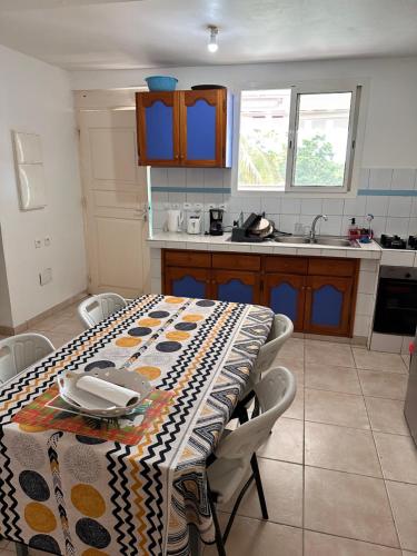 a kitchen with a table with a table cloth on it at La maison du plateau - Évasion Tropicale in Vieux-Habitants
