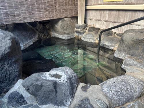 a small pool of water with rocks and a rock at KOUBOUNOYU IKONASOU in Shizuoka