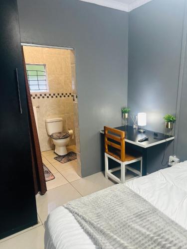 Schlafzimmer mit einem Bett, einem Schreibtisch und einem WC in der Unterkunft SerenityStay 37 on Zebra in Polokwane