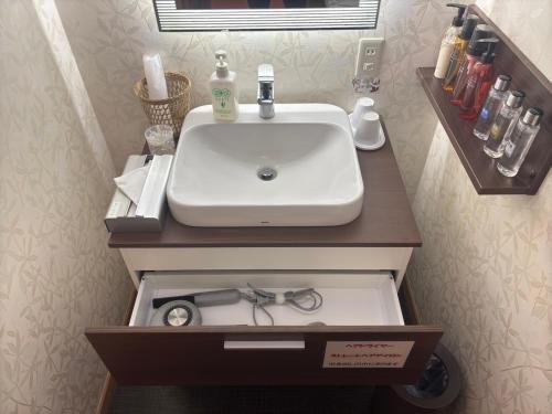 a bathroom sink with a pair of glasses in a drawer at KOUBOUNOYU IKONASOU in Shizuoka