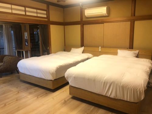 two beds in a room with white sheets at KOUBOUNOYU IKONASOU in Shizuoka