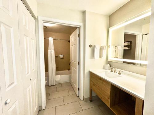 a bathroom with a sink and a mirror and a tub at Staybridge Suites East Stroudsburg - Poconos by IHG in East Stroudsburg