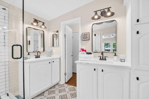 a white bathroom with two sinks and two mirrors at Walk to Blue Jays, Breweries, Marina & Beaches in Dunedin