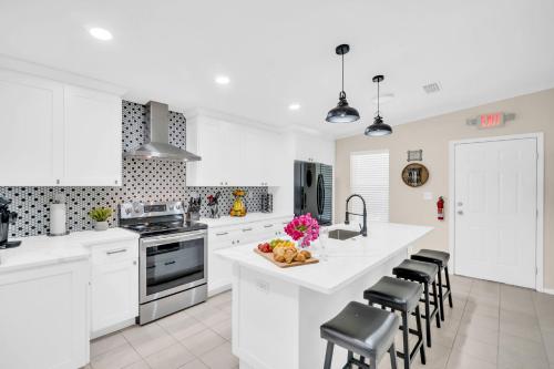 a white kitchen with white cabinets and black chairs at Walk to Blue Jays, Breweries, Marina & Beaches in Dunedin