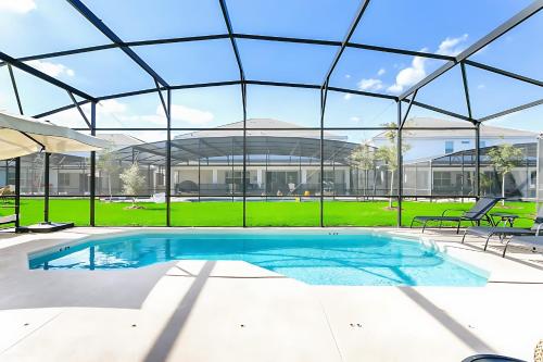 a large swimming pool in a building with a glass ceiling at UPSTAY- 10BR Mansion wPrivate Pool and Games Room in Kissimmee