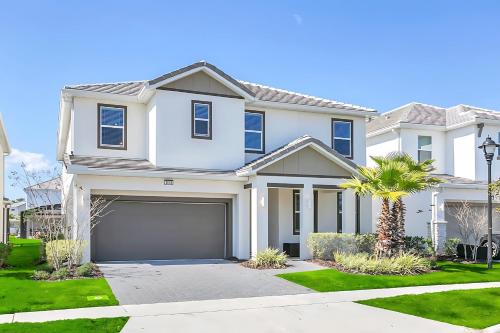 a white house with a garage at UPSTAY- 10BR Mansion wPrivate Pool and Games Room in Kissimmee