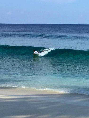 a person riding a wave on a surfboard in the ocean at Scuba Haven Fuvahmulah in Fuvahmulah