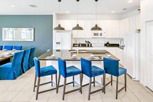 a kitchen with a dining table and blue chairs at UPSTAY- 10BR Mansion wPrivate Pool and Games Room in Kissimmee