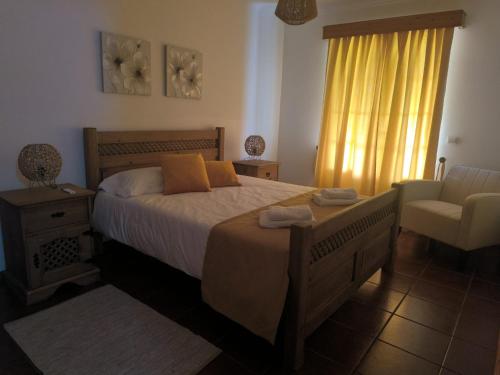 a bedroom with a bed and a chair and a window at Coração das Furnas in Furnas
