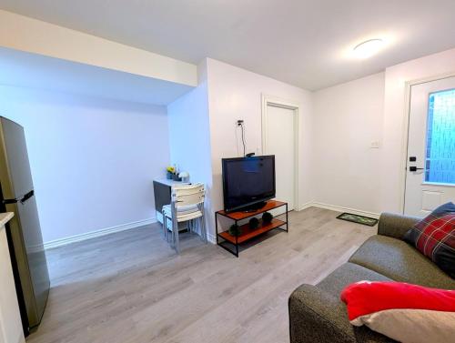a living room with a couch and a flat screen tv at Bright & New 2 Beds Near Subway in Toronto