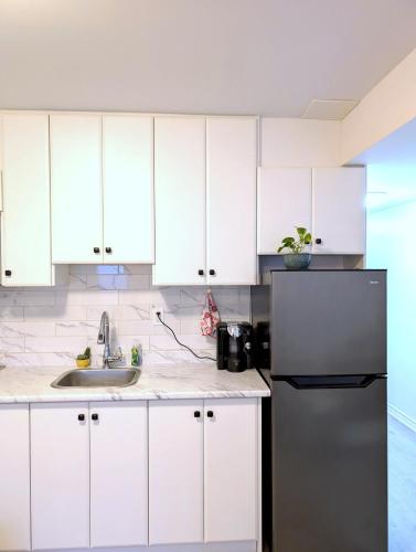 a kitchen with white cabinets and a stainless steel refrigerator at Bright & New 2 Beds Near Subway in Toronto