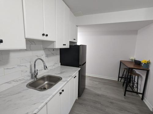 a white kitchen with a sink and a refrigerator at Bright & New 2 Beds Near Subway in Toronto